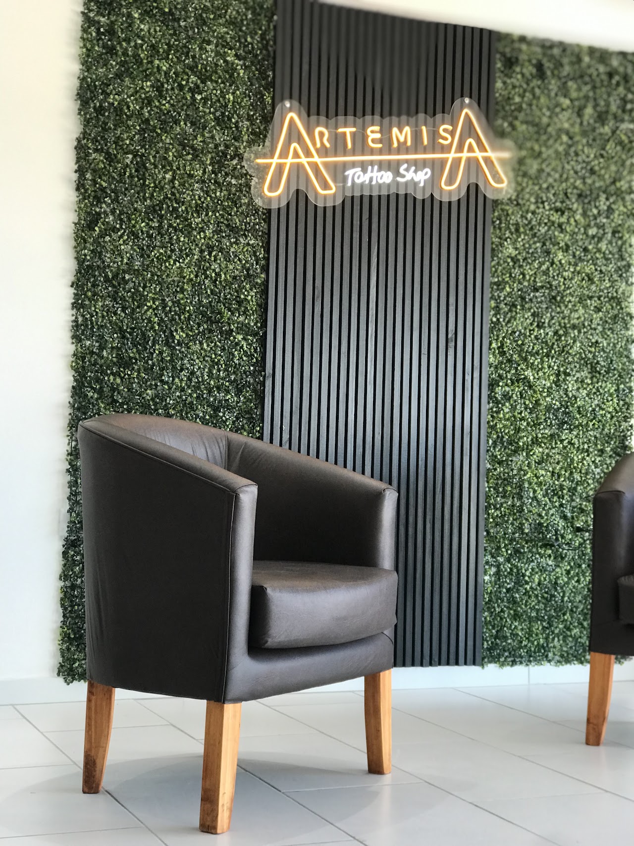 Letrero neón ARTEMISA Tattoo Shop en la recepción del estudio